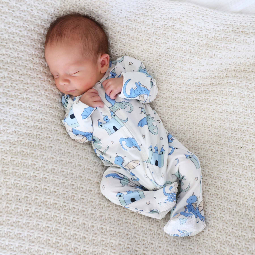 Baby in cozy footed romper with dragon and castle pattern