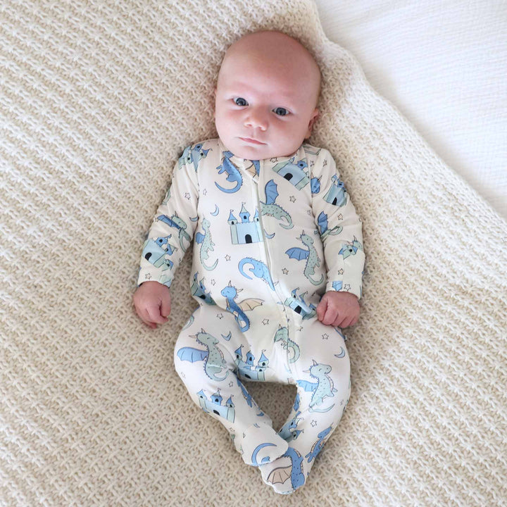 Newborn wearing soft zip-up pajamas with mythical creature design