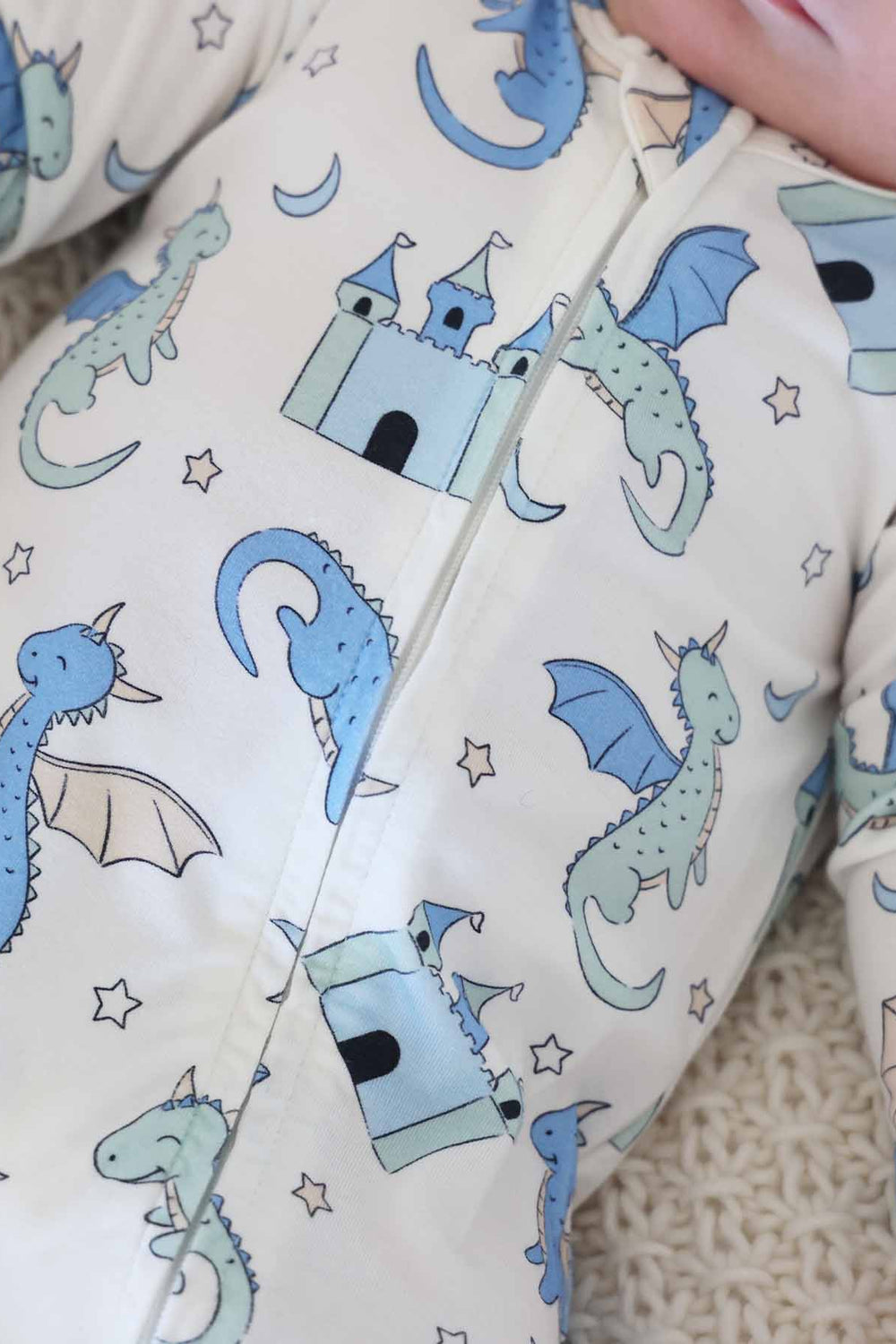 Newborn in dragon and castle print zip-up onesie