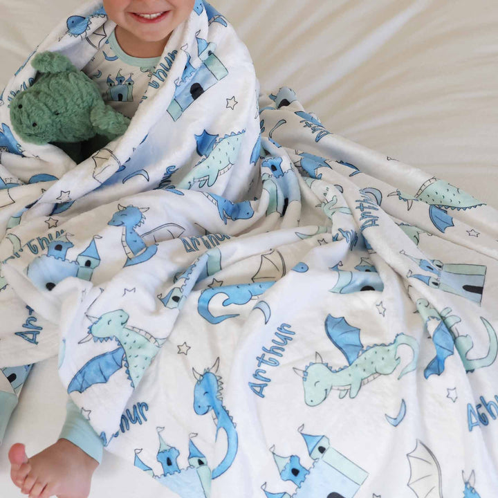 child wrapped in dragon personalized blanket holding a dragon stuffed animal