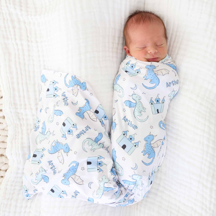 baby boy wrapped in personalized swaddle blanket with pastel dragons and castles