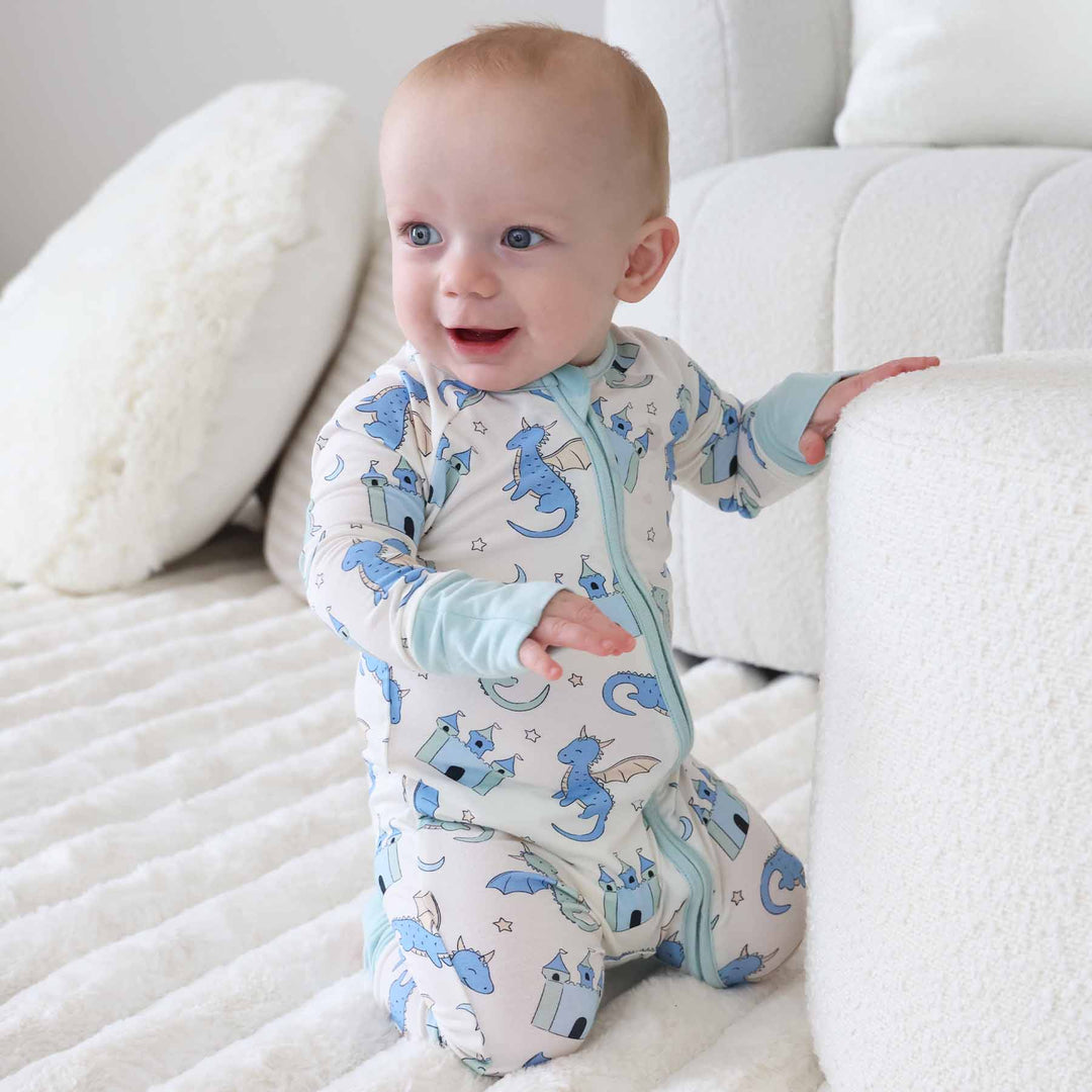 Infant boy wearing cream romper with dragon and mint trim accents