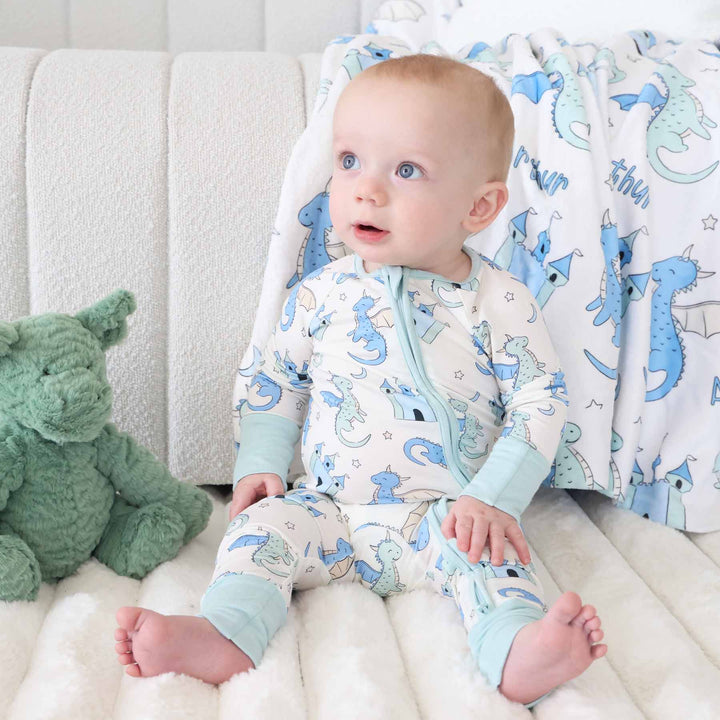 Baby in dragon and castle zip romper sitting on floor