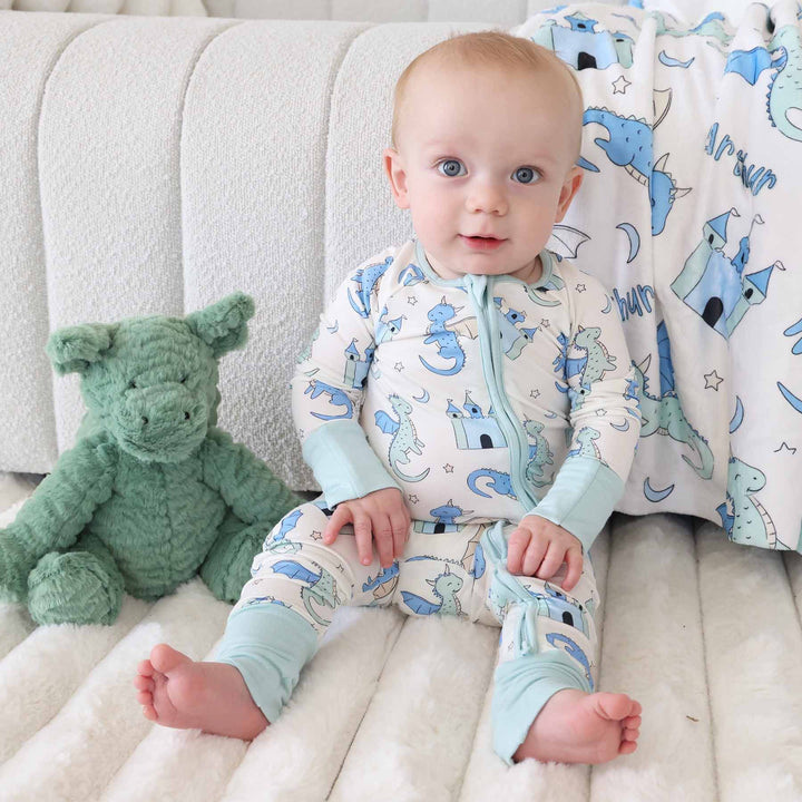 Baby sitting barefoot wearing dragon romper with zipper front