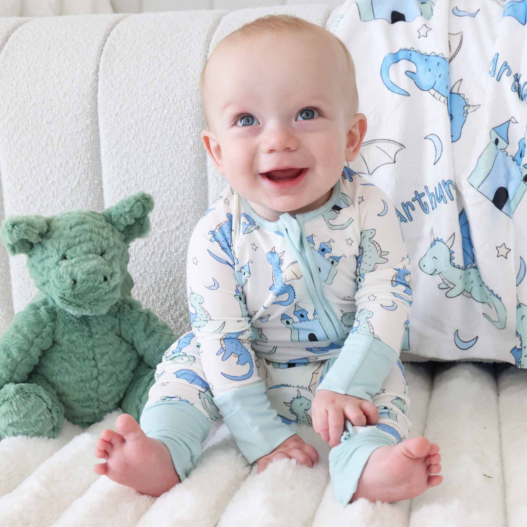 Infant dressed in zip romper with whimsical dragon and castle design