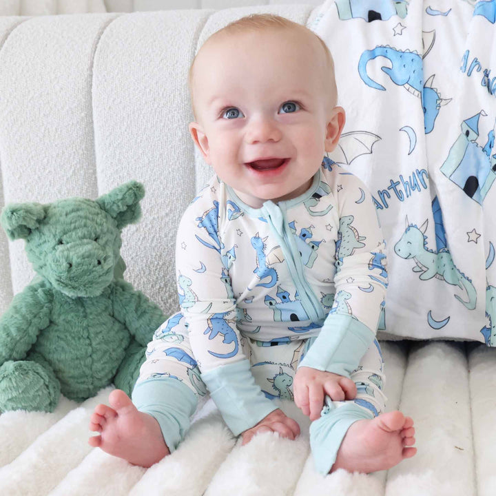 Infant dressed in zip romper with whimsical dragon and castle design