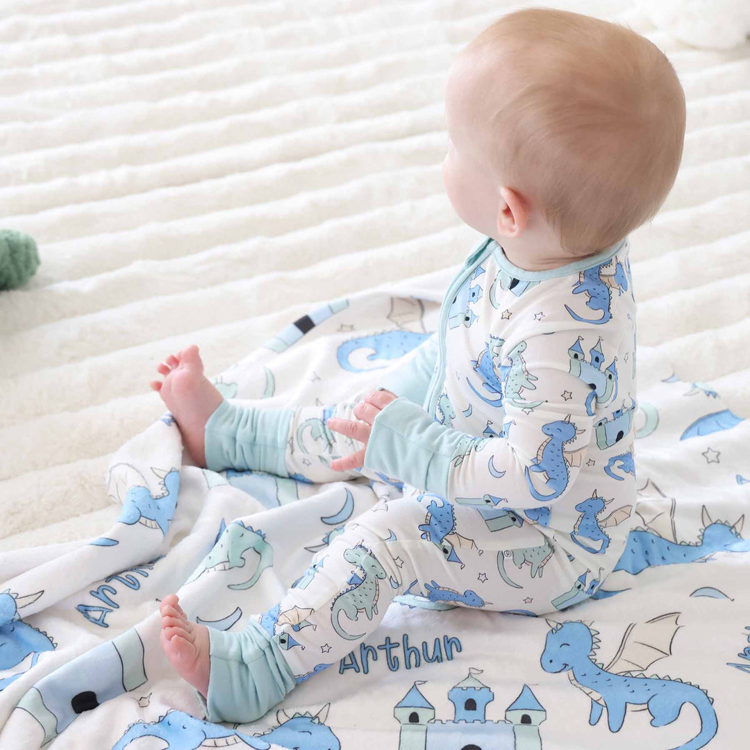 Infant boy in convertible romper with dragons and castles on matching blanket 