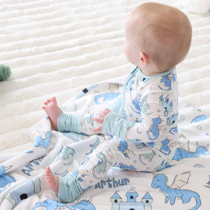 Infant boy in convertible romper with dragons and castles on matching blanket 