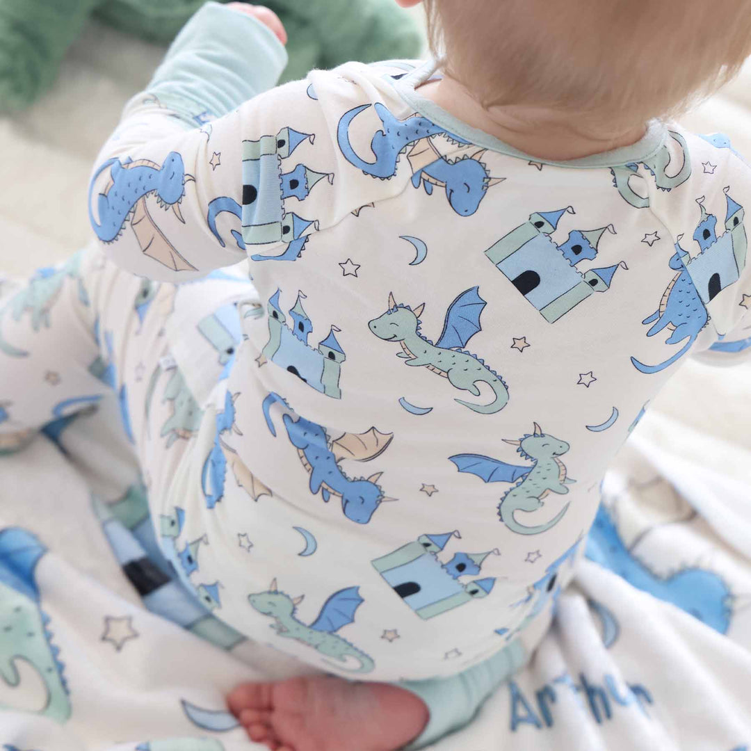 Baby in zipper romper with mint cuffs featuring dragon and castle print