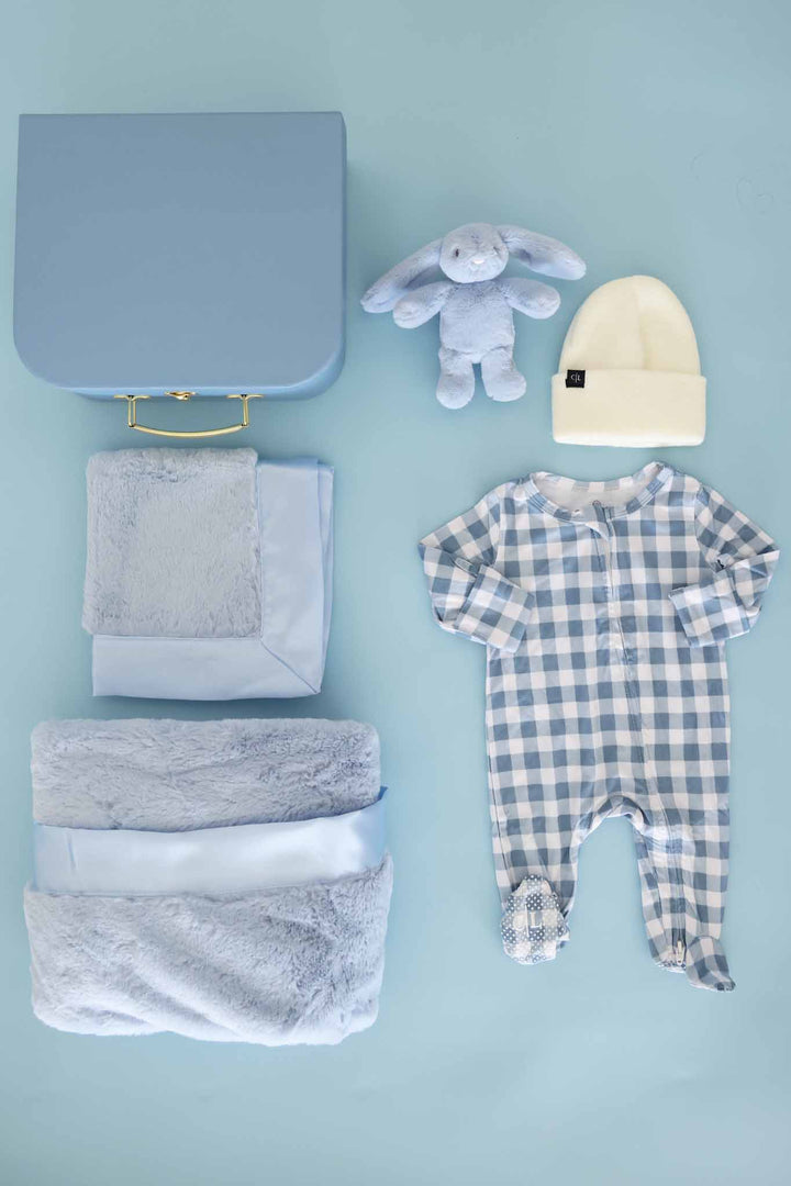 contents of newborn keepsake box with blue lovey, blanket, bunny, beanie and gingham footie 