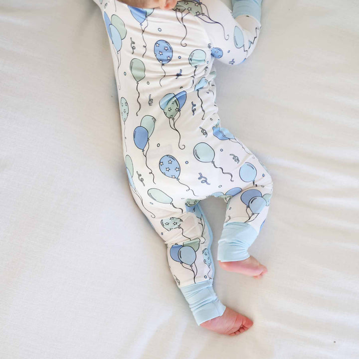 baby boy laying on stomach wearing balloon pajama romper 