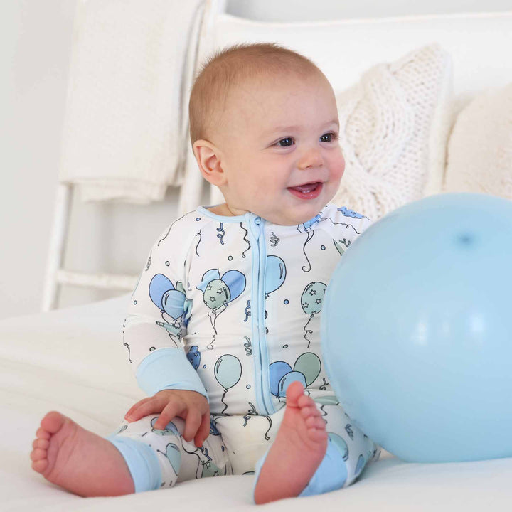boy wearing balloon convertible zip romper holding a balloon