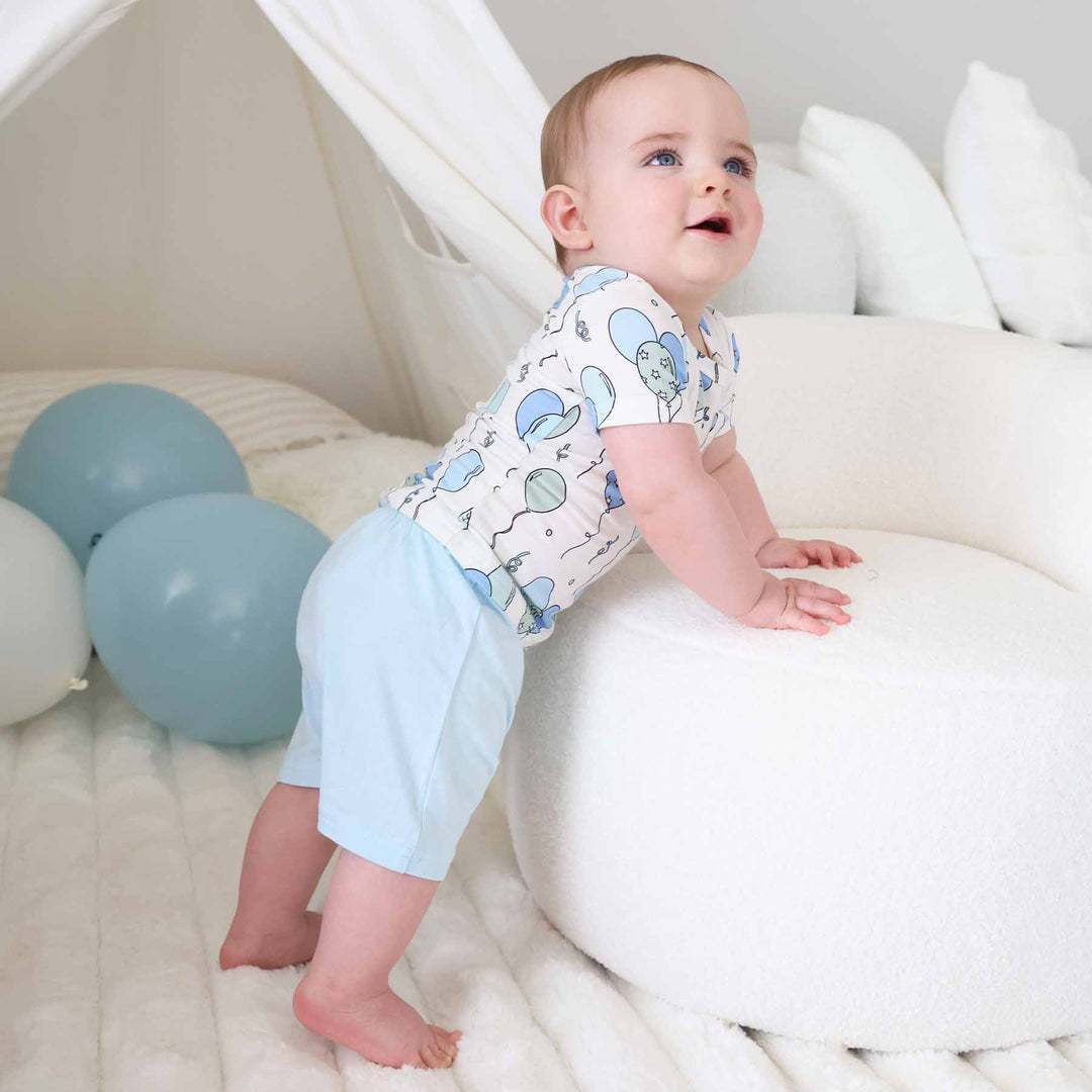 bow leaning on ottoman wearing a short sleeve balloon shirt with matching light blue shorts 