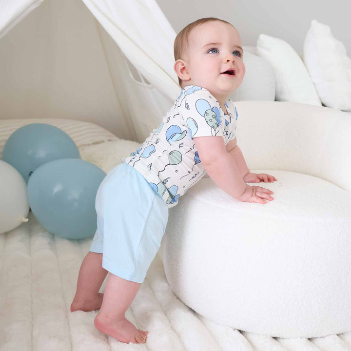 bow leaning on ottoman wearing a short sleeve balloon shirt with matching light blue shorts 