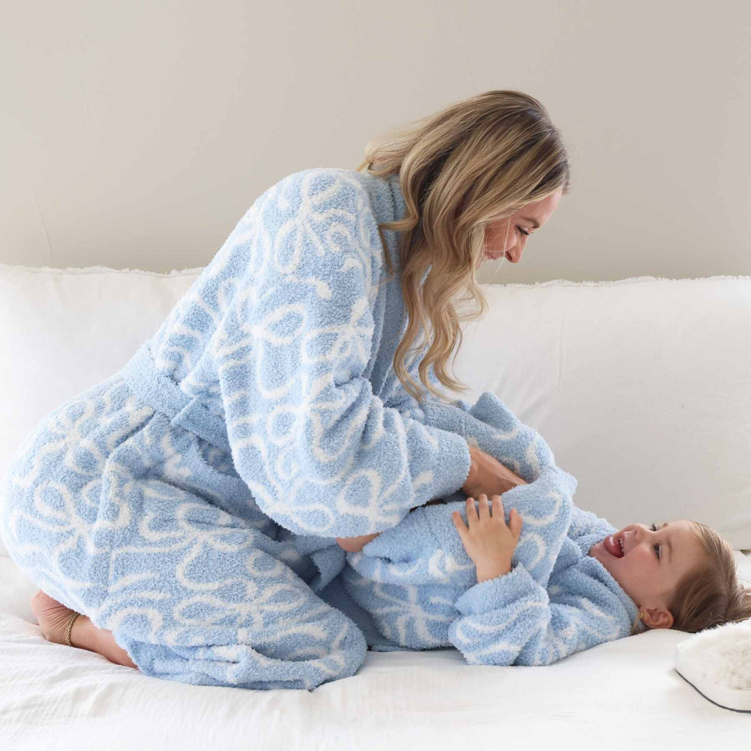 mom tickling daughter on a bed in cuddlelane plush robe blue-tiful bows 