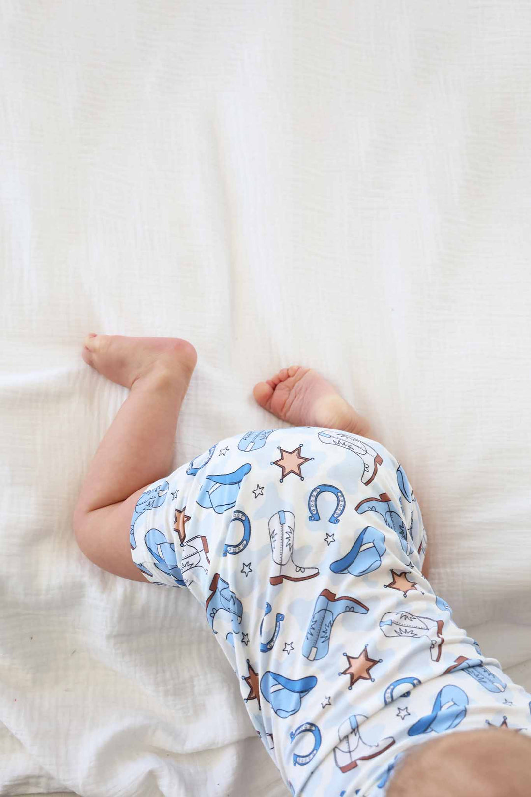 crawling baby boy in blue western themed button romper 