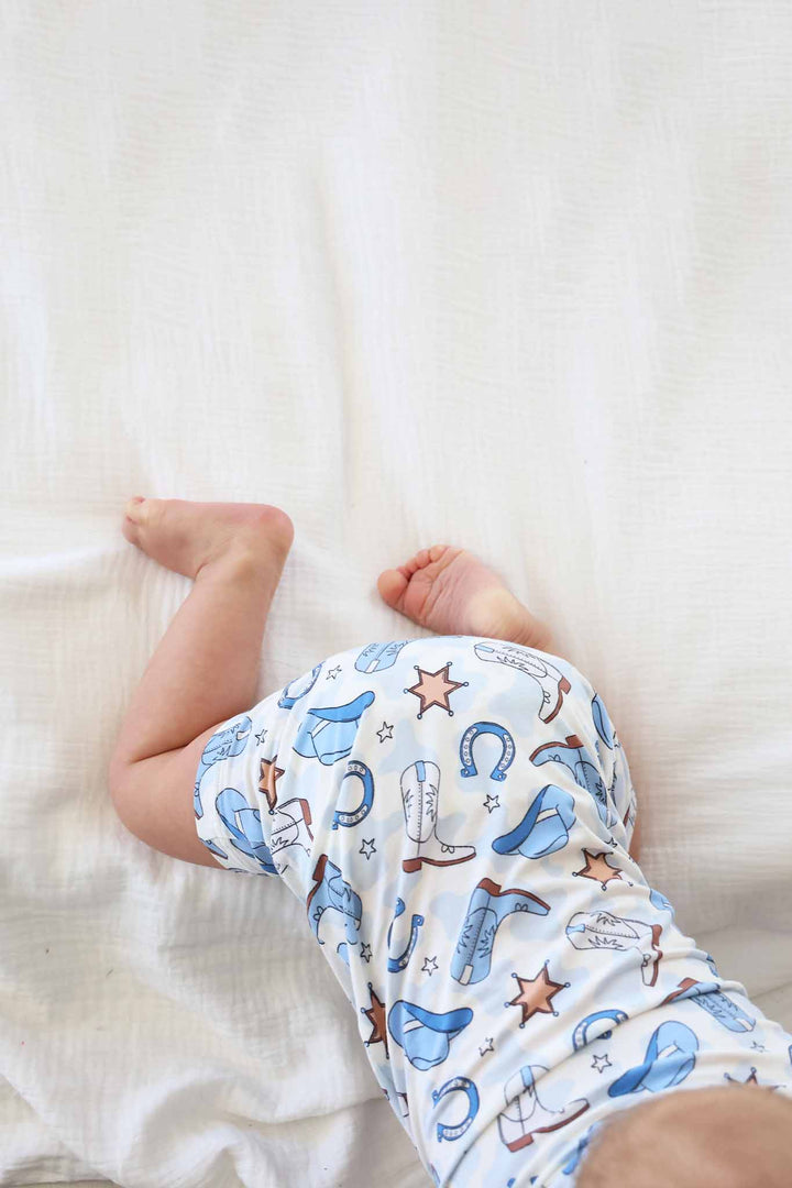 crawling baby boy in blue western themed button romper 
