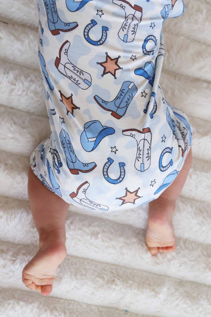 daytime romper for baby and toddler boys in blue cowboy print with hats, boots, horseshoes and sheriff stars 