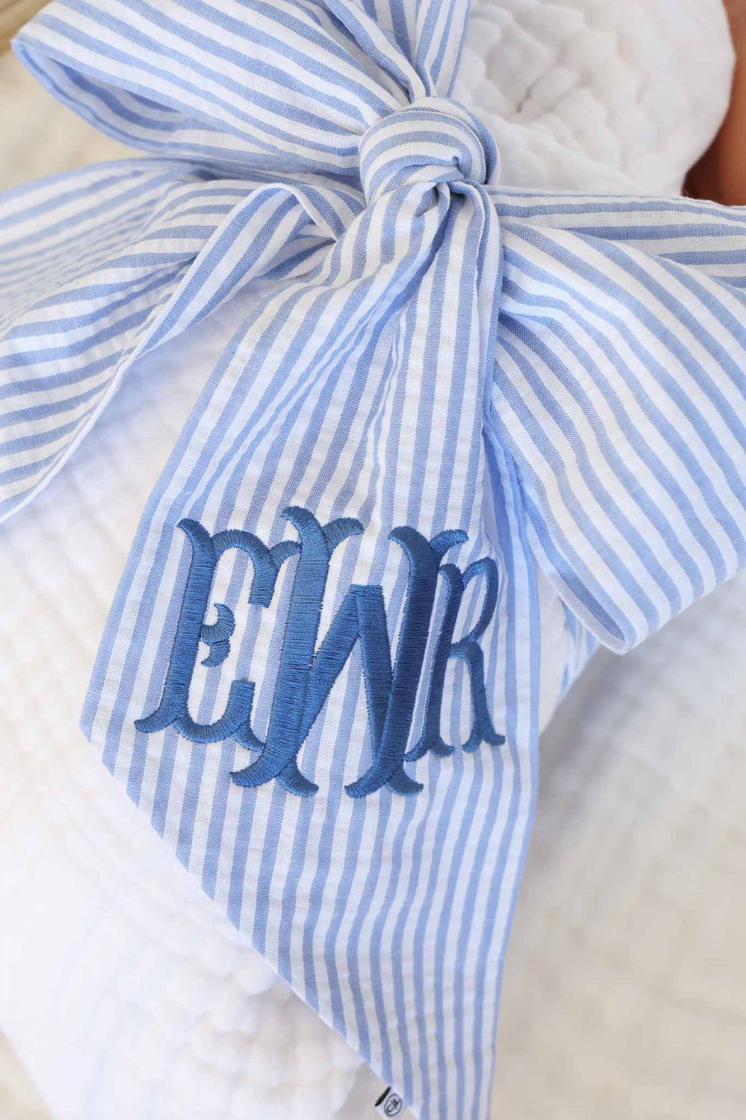 closeup of blue seersucker monogrammed sash for baby boys with dusty blue thread 
