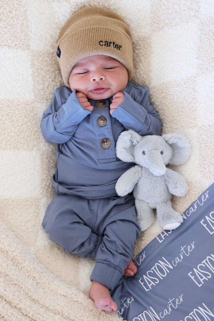 boy laying on checkered blanket in denim blue two piece set with a matching beanie 