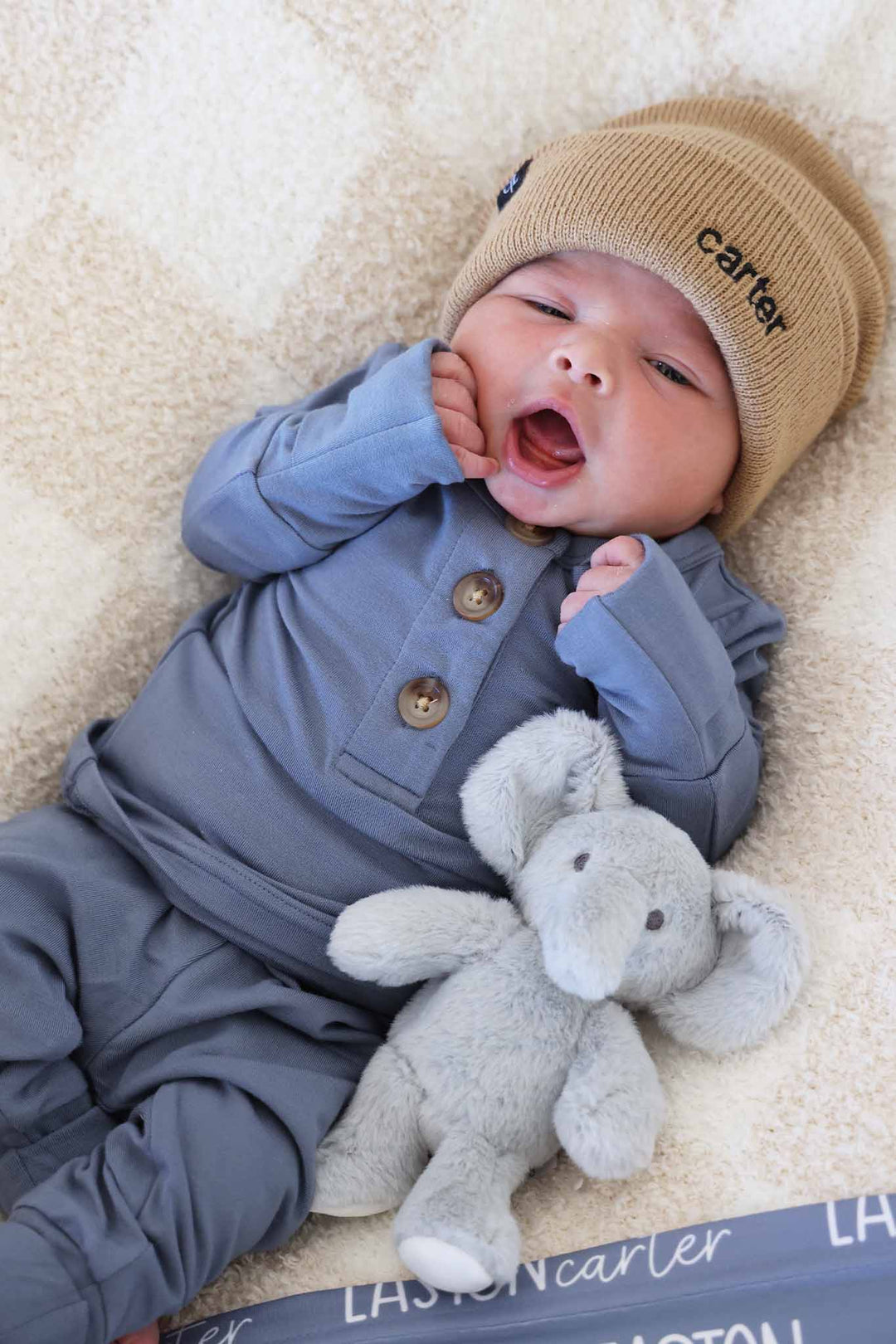 yawning baby boy in blue jean two piece bamboo set with buttons and matching beanie 