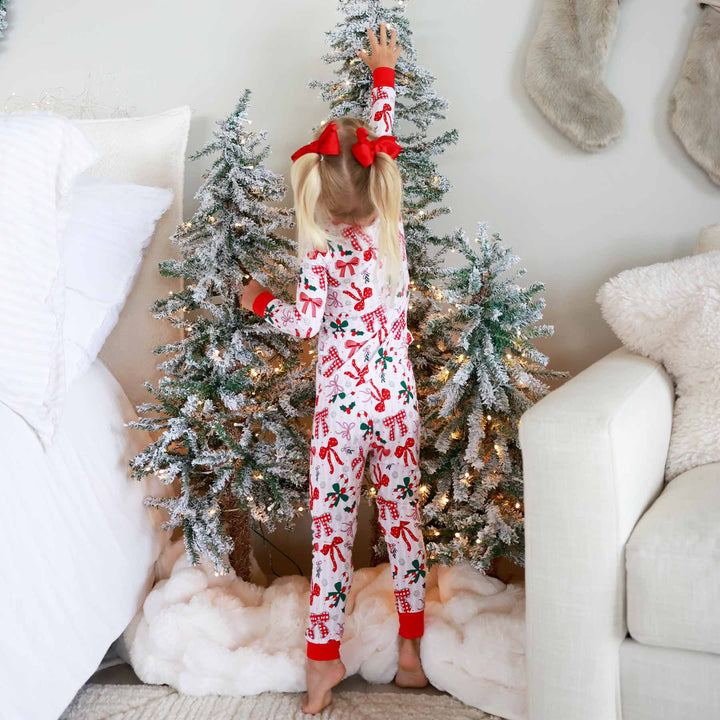 Little girl wearing the Bow What Fun Two Piece Pajama Set while touching christmas tree