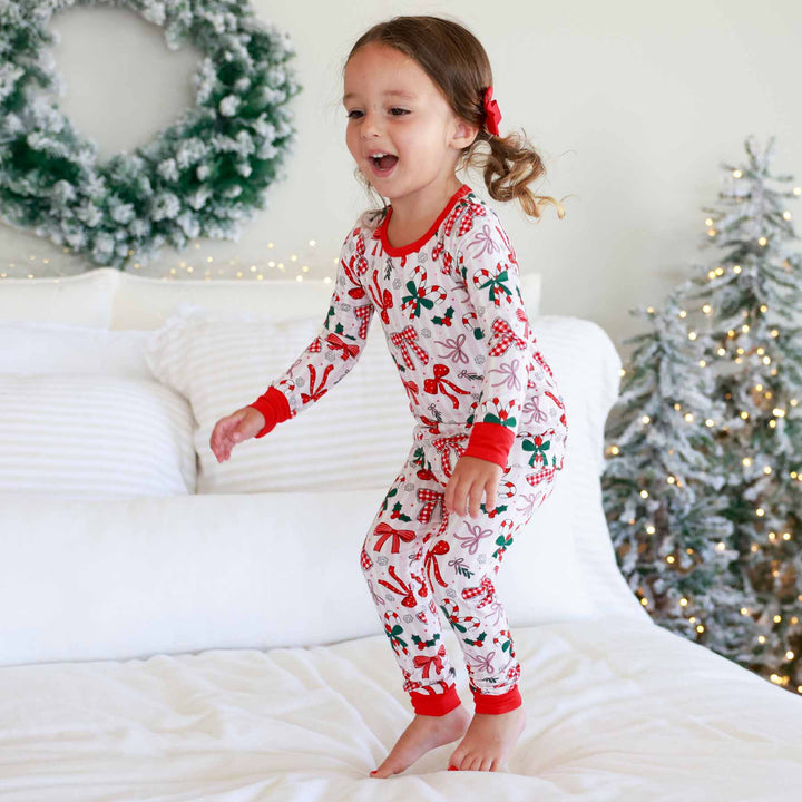 Little girl wearing the Bow What Fun Two Piece Pajama Set while jumping on bed
