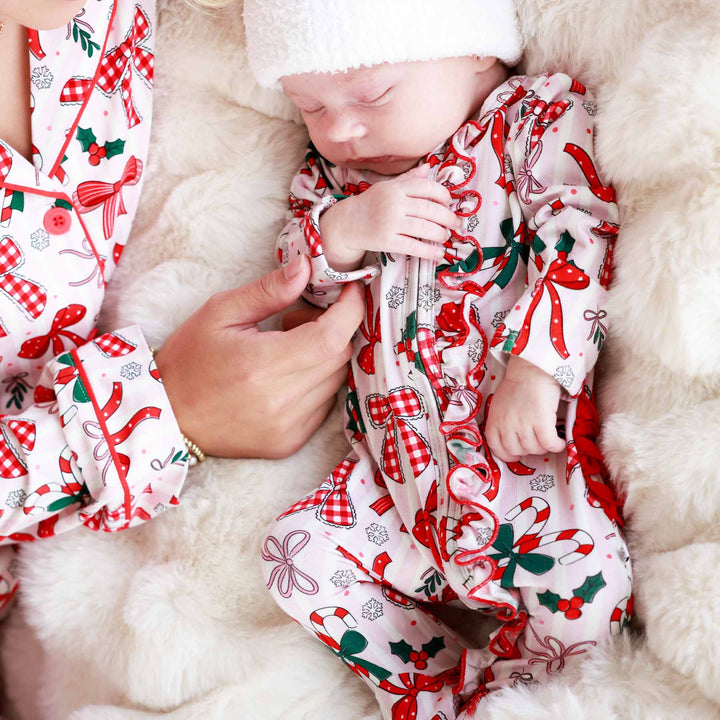 Baby wearing the Bow What Fun Ruffle Zipper Footie with a mini santa hat and matching momma