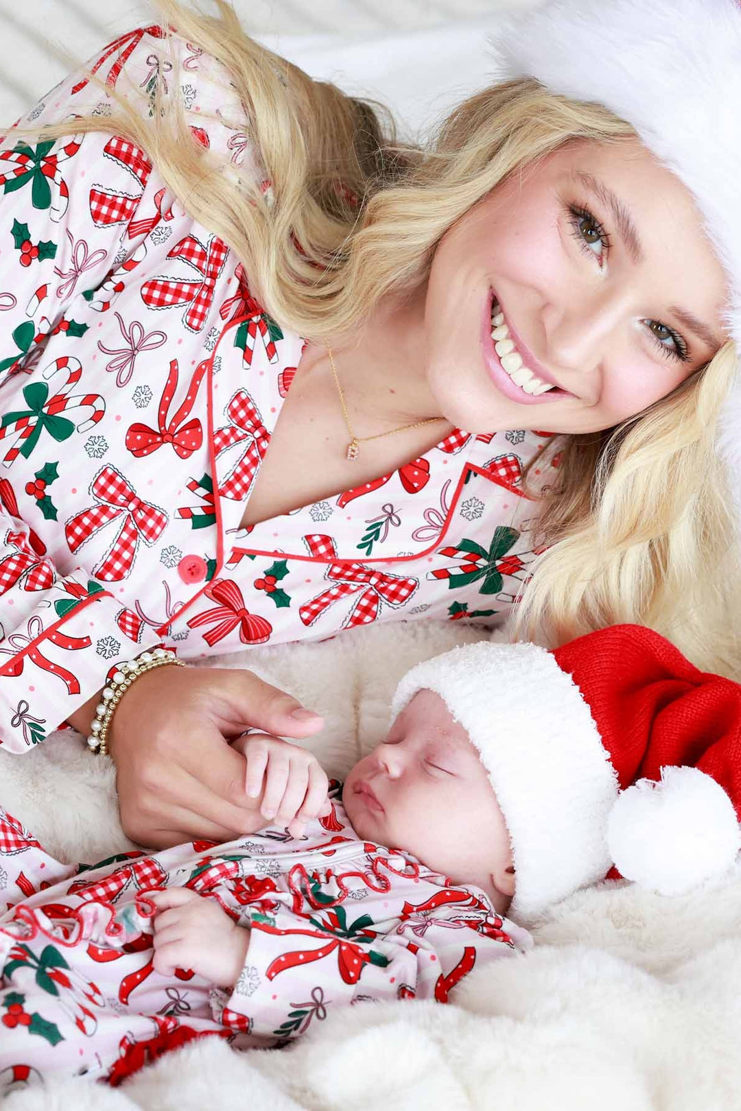 Mother and baby in matching Caden Lane holiday pajamas featuring bows, candy canes, and holly