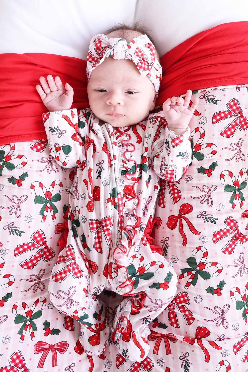 Baby wearing the Bow What Fun Ruffle Zipper Footie with matching headband.