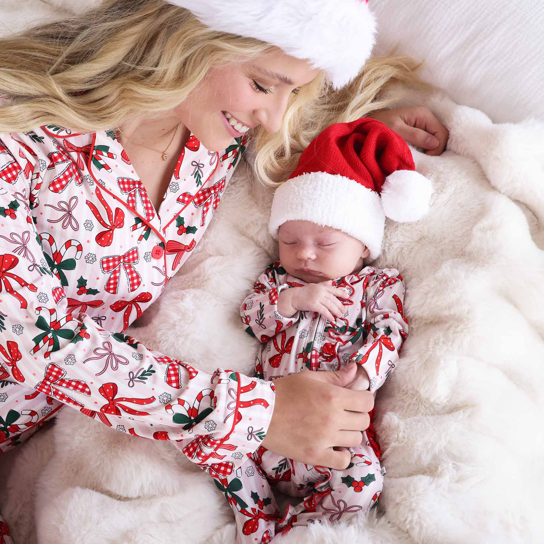 Baby wearing the Bow What Fun Ruffle Zipper Footie with a mini santa hat and matching momma