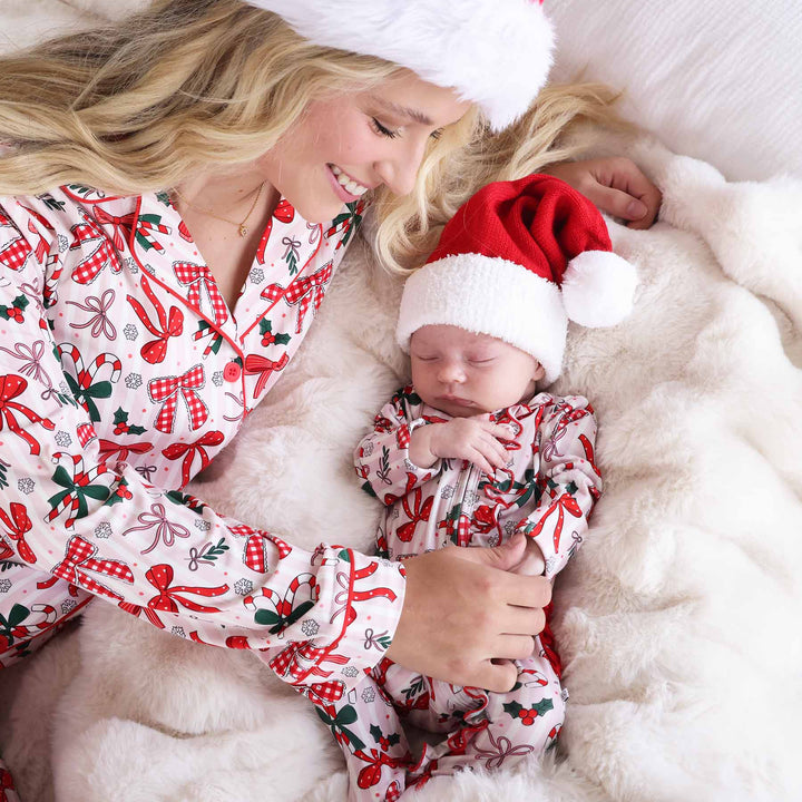 Baby wearing the Bow What Fun Ruffle Zipper Footie with a mini santa hat and matching momma