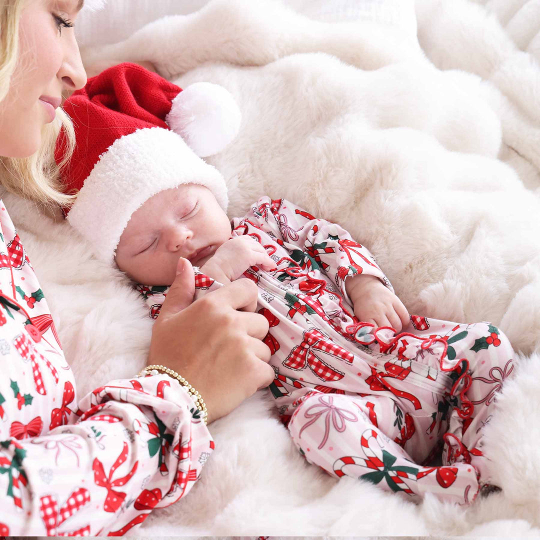 Baby wearing the Bow What Fun Ruffle Zipper Footie with a mini santa hat and matching mom.