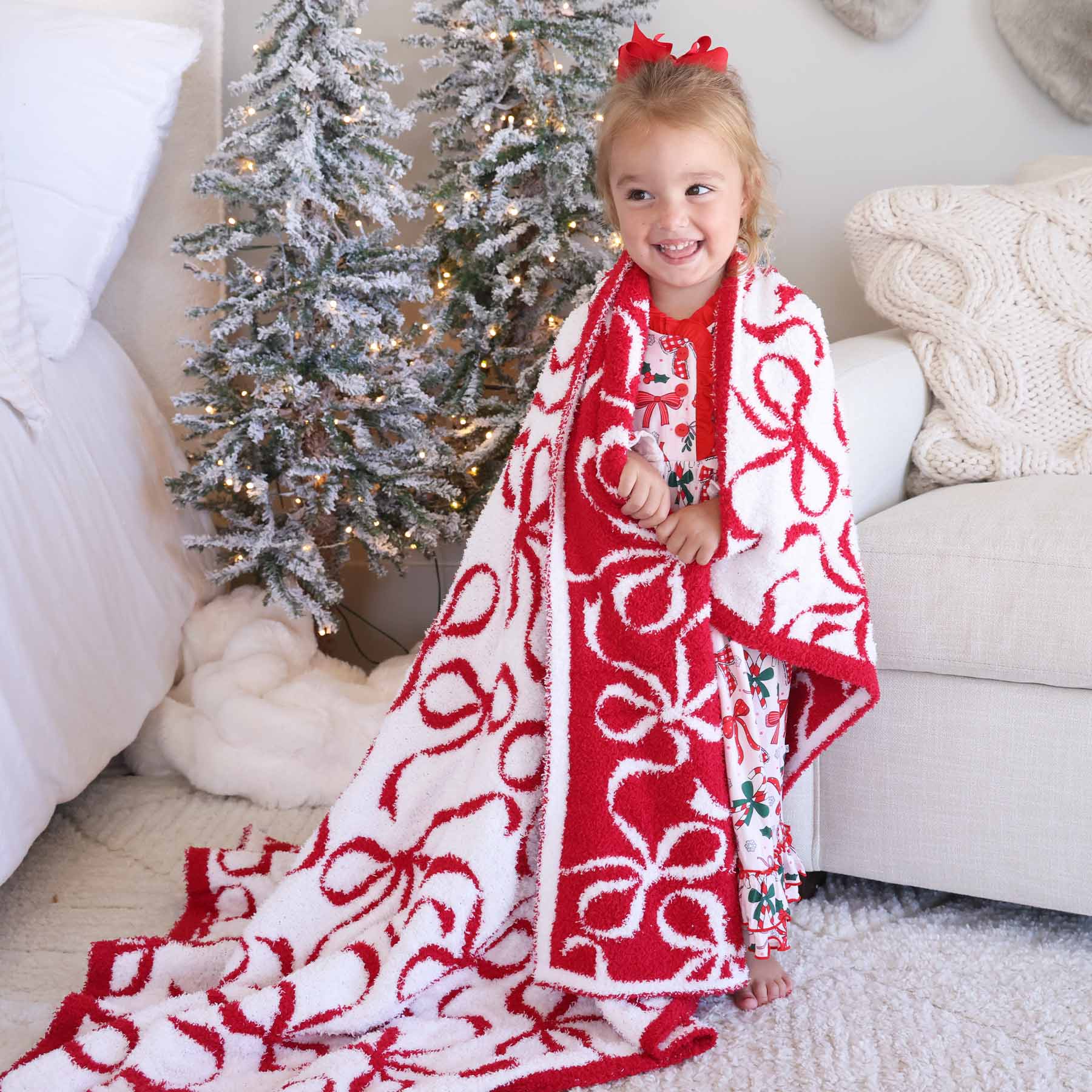 girl wrapped in a microfiber blanket that is white with red bows on one side and red with white bows on the other side