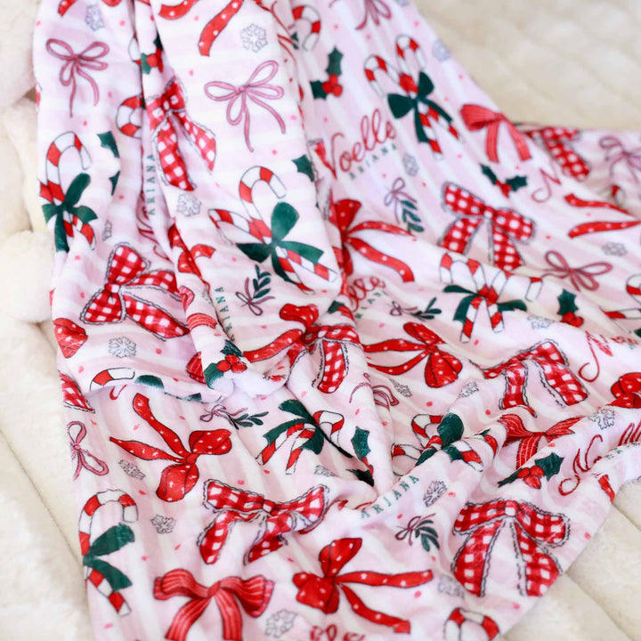 personalized name blanket for girls christmas themed with red bows, candy canes and holly berries