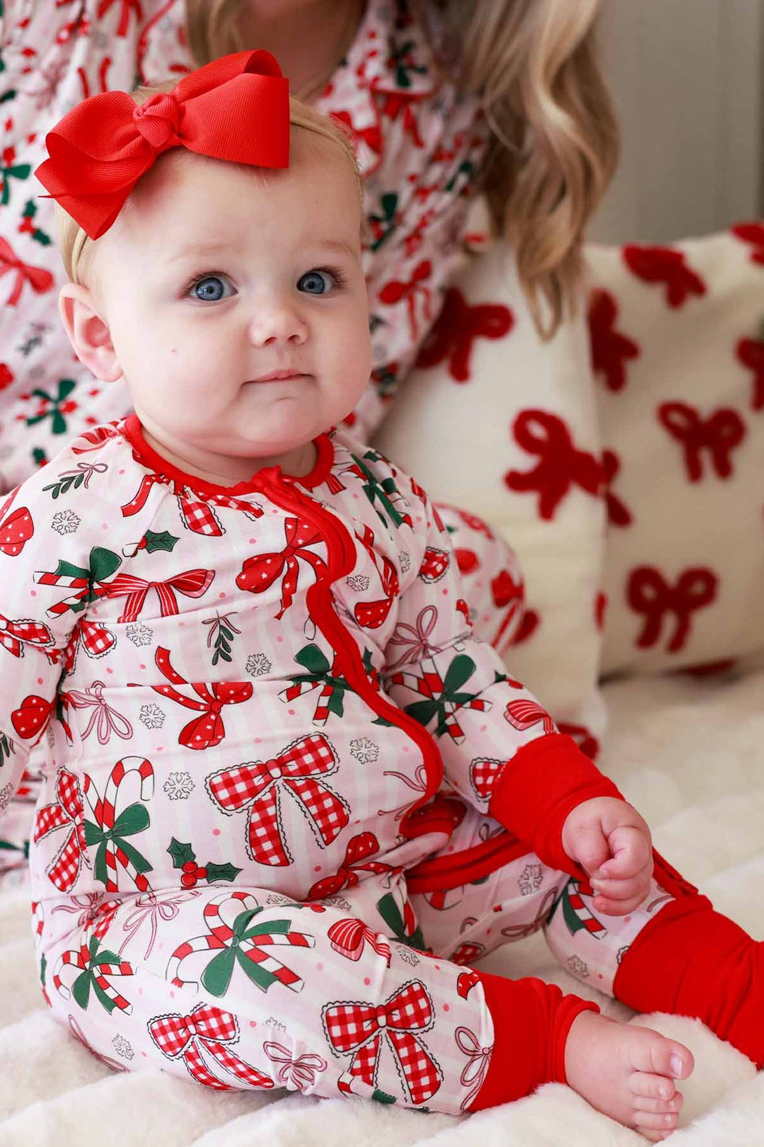Baby and mom in red and green Caden Lane matching outfits with bows and candy canes