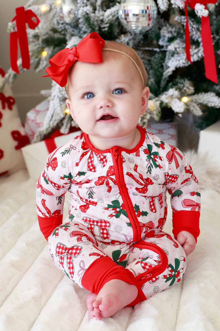 Baby in red and green Caden Lane romper with bows and candy canes