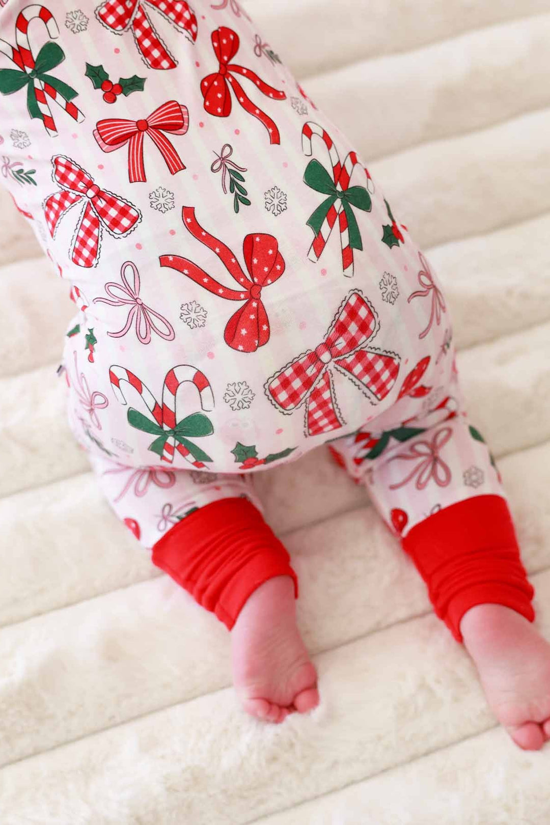 Baby in red and green Caden Lane romper with bows and candy canes