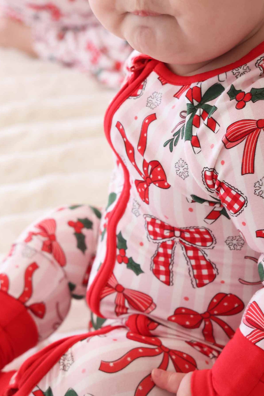 Baby in red and green Caden Lane romper with bows and candy canes