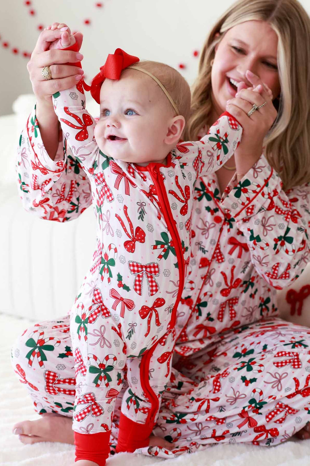 Baby and mom in red and green Caden Lane matching outfits with bows and candy canes