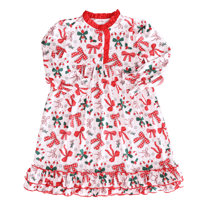 Flat lay of a festive girls’ Christmas nightgown with red bows, candy canes, holly, and snowflake print, trimmed with red ruffles.