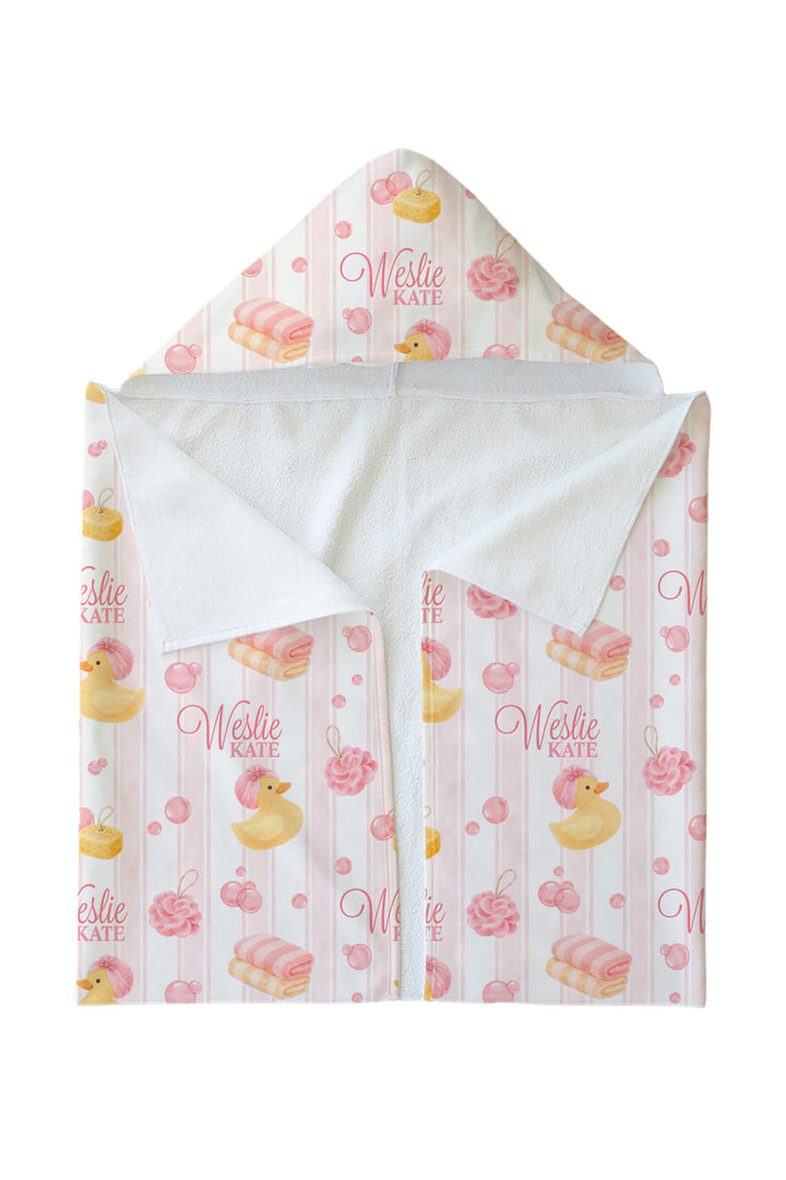 Personalized white bamboo kids hooded towel with pink rubber duck and stripe print, shown folded with custom name embroidered on exterior