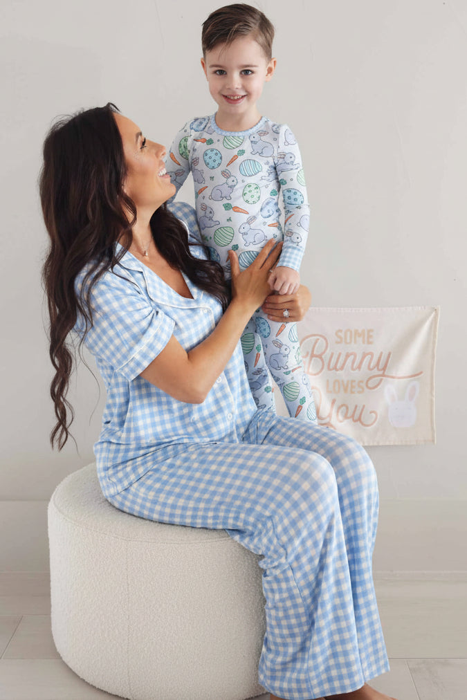mom sitting on ottoman wearing a blue and white gingham lounge set with son matching easter pajamas 