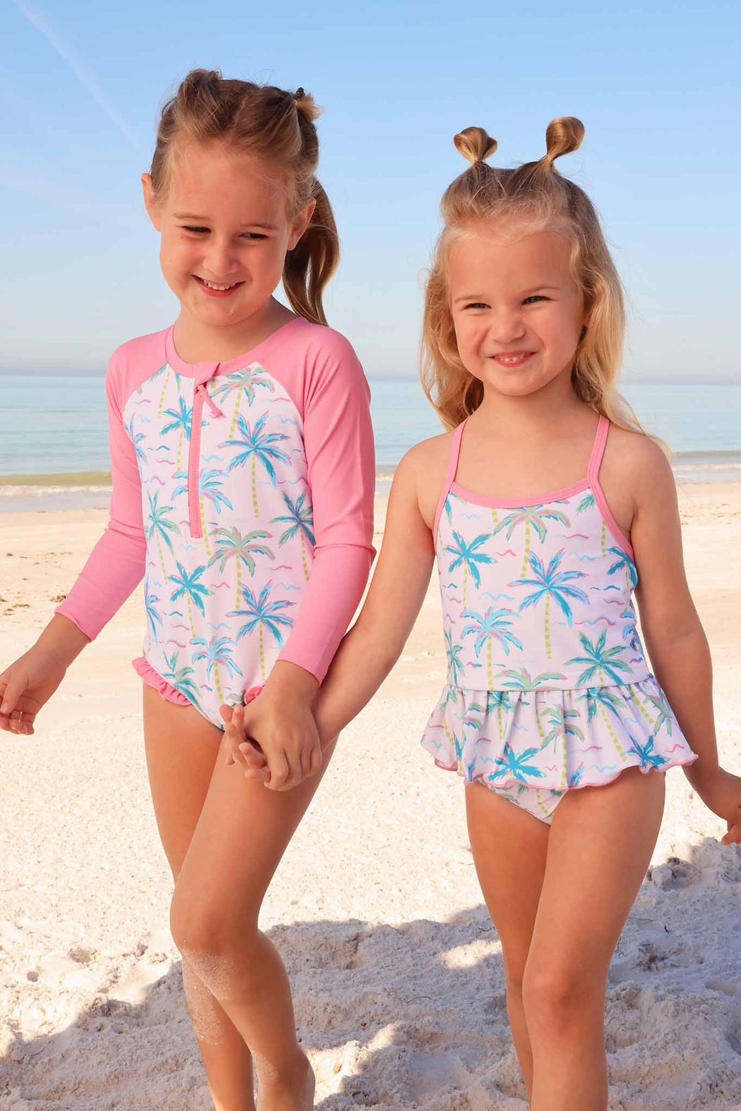 sisters holding hands wearing matching neon palm tree swimsuits