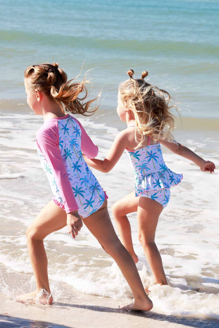 two girls running on beach in palm tree swimsuits 
