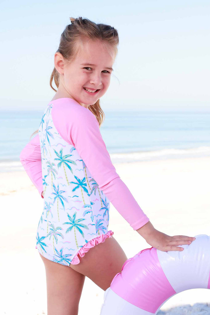 girl wearing blue lagoon long sleeve rash guard with front zipper leaning on innertube