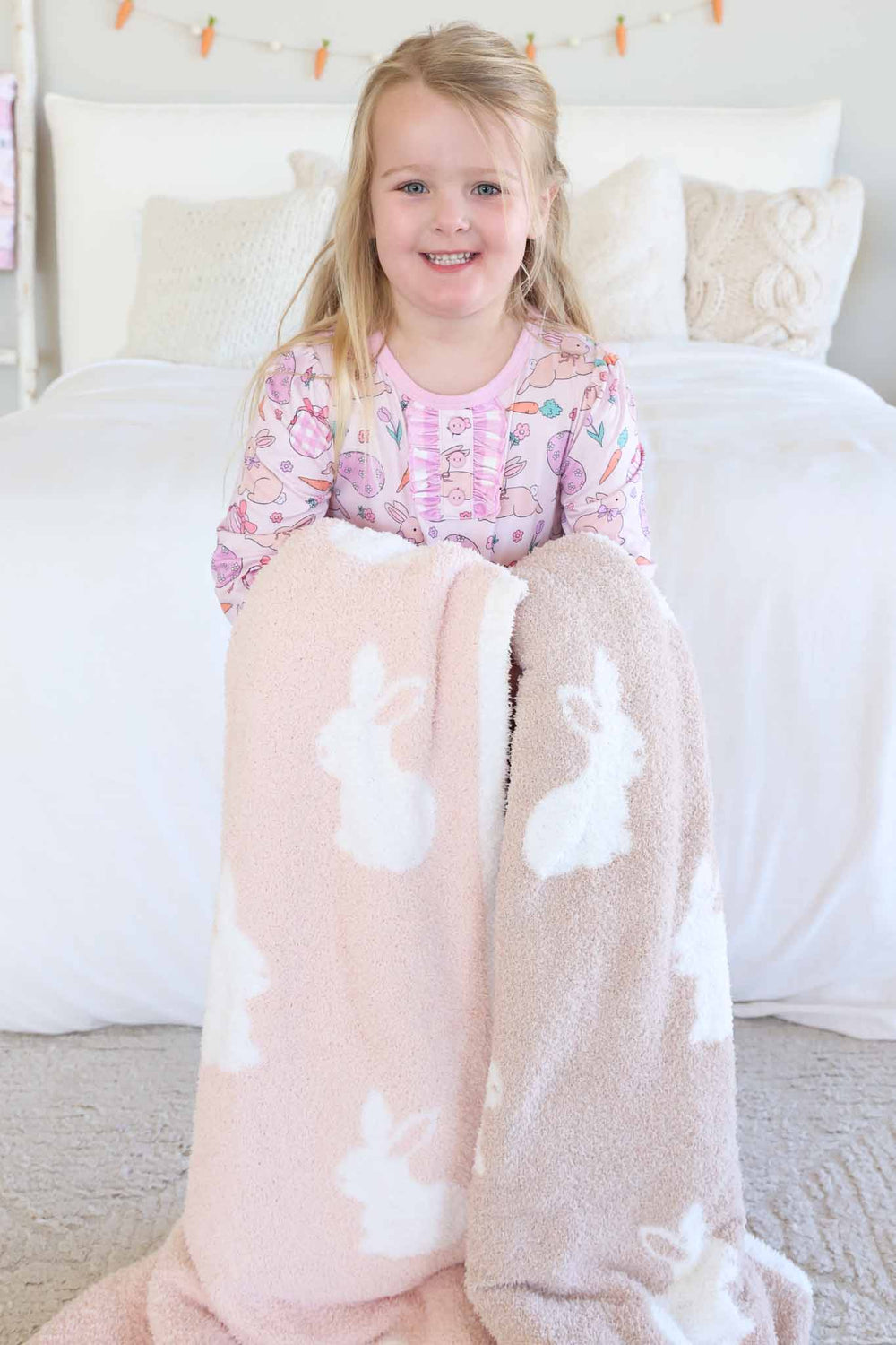 girl in easter nightgown holding pink and neutral bunny cuddlelane blankets for easter 