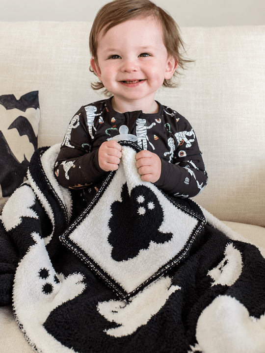 boy holding cuddlelane ghost lovey with pacifier and matching blanket on lap 