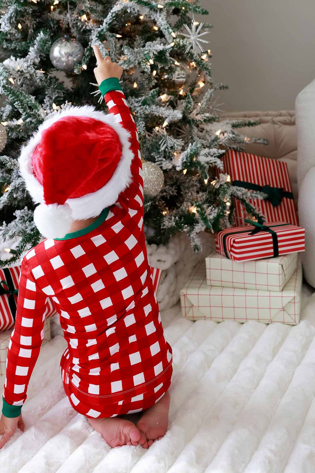 Child in red, green, and white plaid Caden Lane pajamas with Santa hat