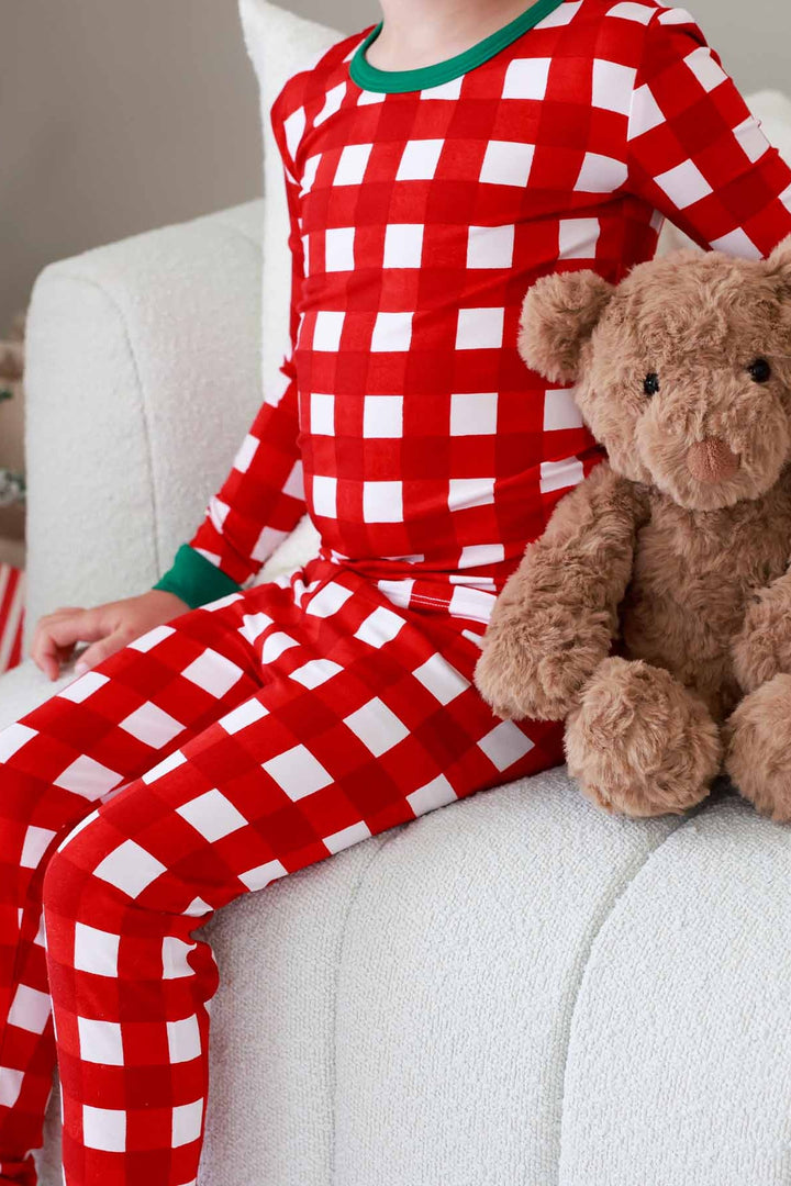 Child sitting in chair wearing red, green, and white plaid Caden Lane pajamas